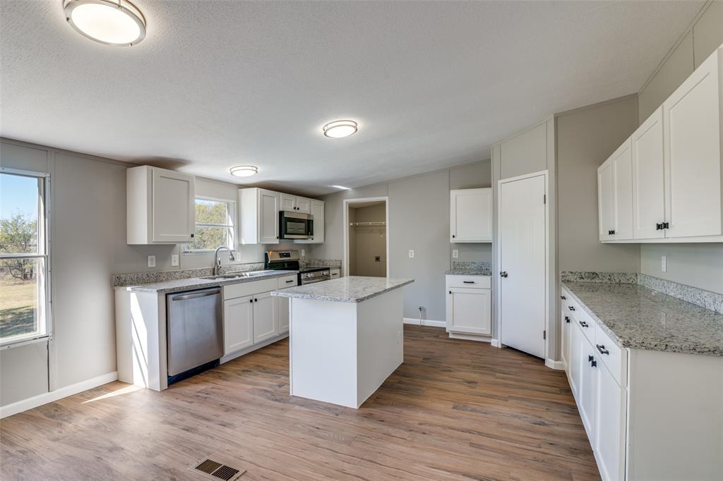 3176 North Ridge Crandall, TX 75114 - Photo 9 of 24 a kitchen with stainless steel appliances granite countertop a stove top oven a sink dishwasher and a refrigerator with wooden floor