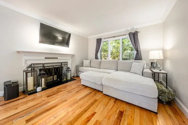 a view of a livingroom with furniture wooden floor windows and a fireplace
