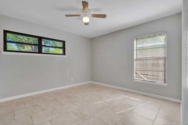an empty room with windows and ceiling fan
