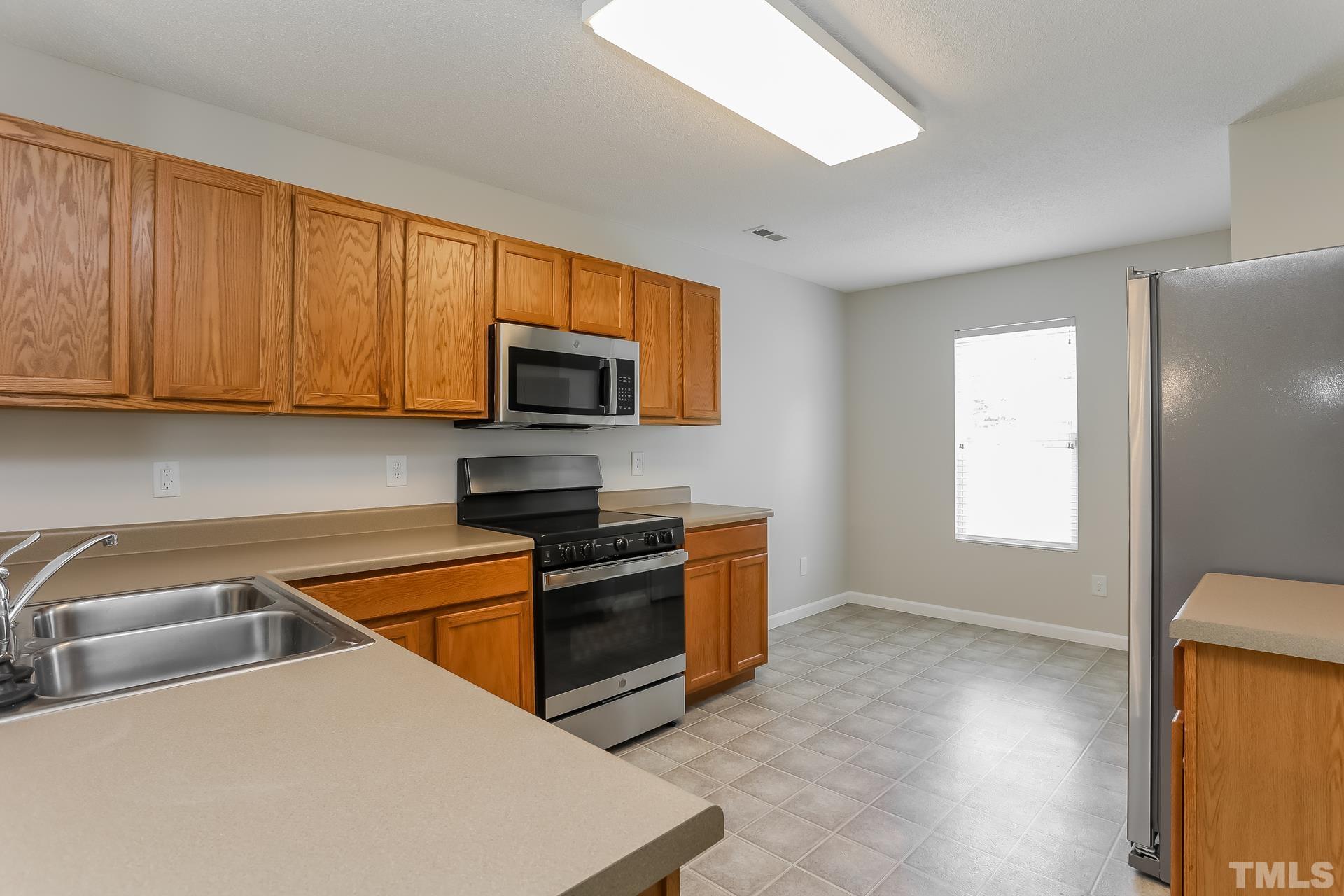3618 Mountain Brook Circle Durham, NC 27704 - Photo 7 of 15 a kitchen with stainless steel appliances granite countertop a sink a stove a microwave a refrigerator a cabinets and wooden floor