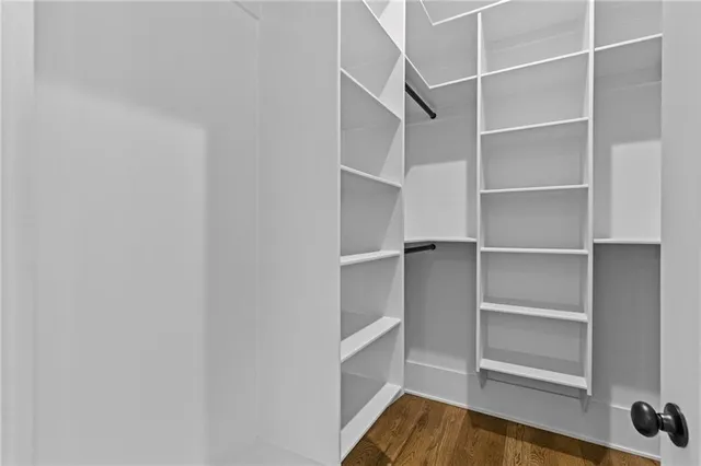 an empty room with wooden floor chandelier fan and windows