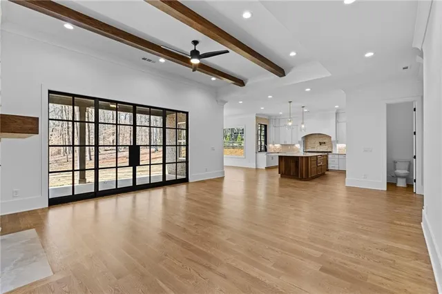 an empty room with wooden floor fireplace and windows