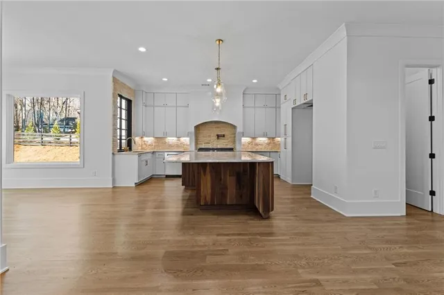 a kitchen with granite countertop a stove a sink and dishwasher with white cabinets