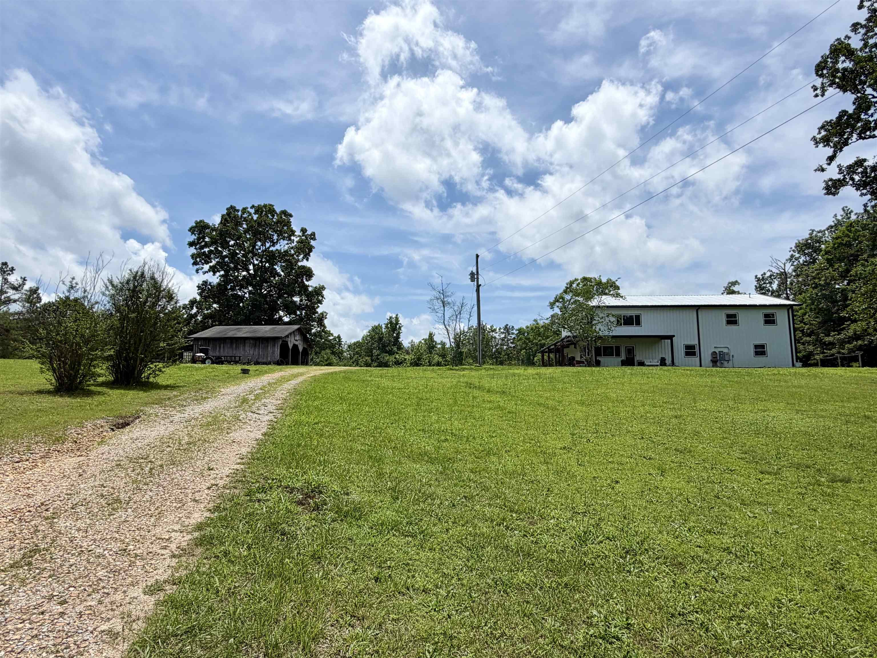 3670 Peavine Road Middleton, TN 38052 - Photo 36 of 36 Gravel driveway leading to a white metal-sided residence with multiple windows and a covered porch