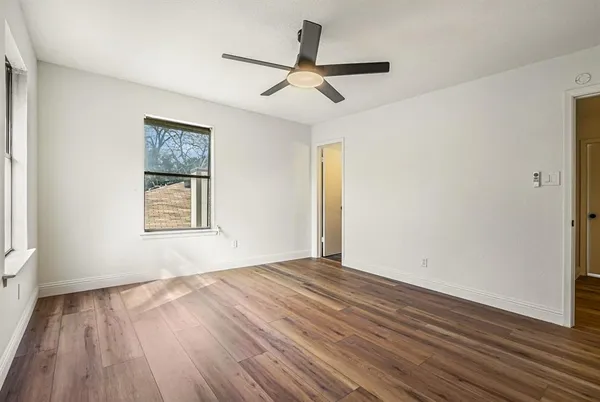a view of an empty room with wooden floor and a window