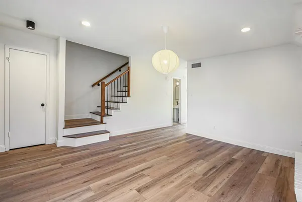 a view of an empty room with wooden floor and stairs