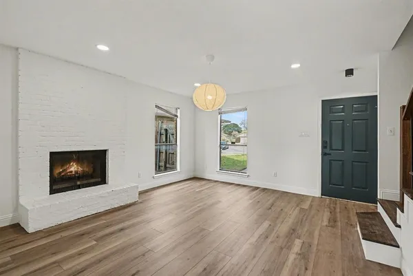 a view of an empty room with window and wooden floor