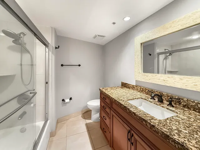 a bathroom with a granite countertop sink a mirror and a toilet