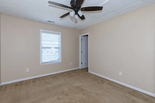 an empty room with a ceiling fan and windows