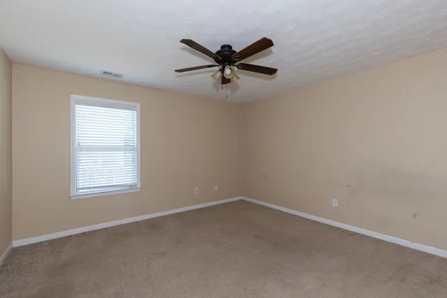 an empty room with a window and a ceiling fan