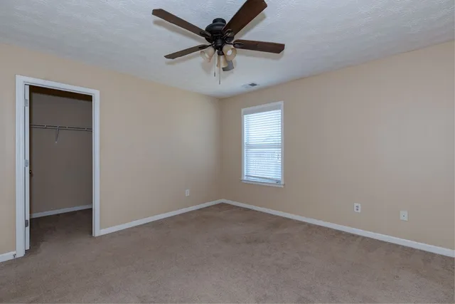 an empty room with a window and a fan
