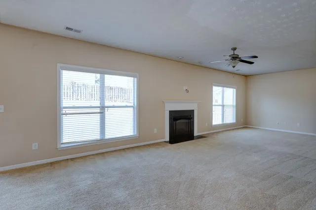 an empty room with windows and ceiling fan