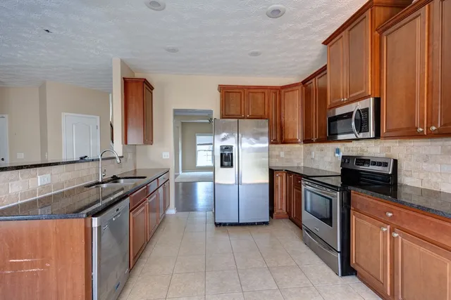 a kitchen with stainless steel appliances granite countertop a stove top oven a sink dishwasher a refrigerator and a microwave oven