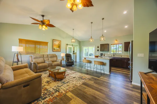 a living room with furniture kitchen view and a wooden floor