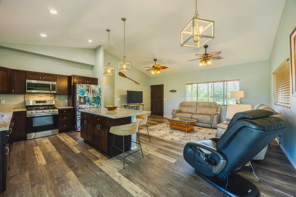 a living room with stainless steel appliances kitchen island granite countertop a stove and a wooden cabinets