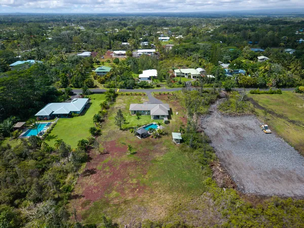 an aerial view of residential houses with outdoor space and trees