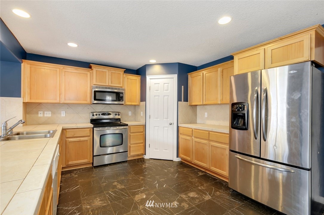 16410 Northeast 12th Court Ridgefield, WA 98642 - Photo 7 of 25 a kitchen with stainless steel appliances a refrigerator sink and microwave