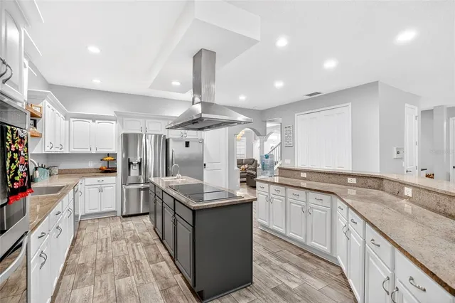 a large kitchen with stainless steel appliances granite countertop a lot of counter space and wooden floors