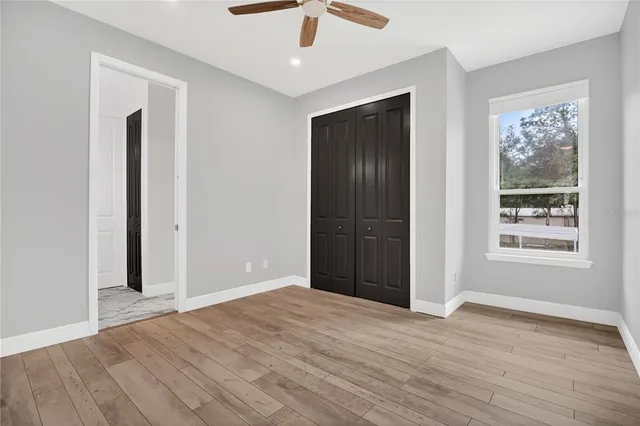 an empty room with wooden floor cabinet and windows