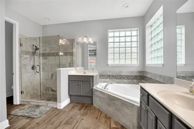 a bathroom with a granite countertop tub a sink and a large mirror