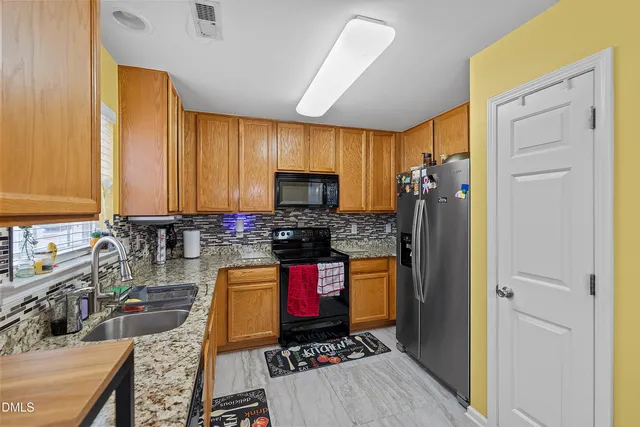 a kitchen with stainless steel appliances granite countertop a stove refrigerator and sink