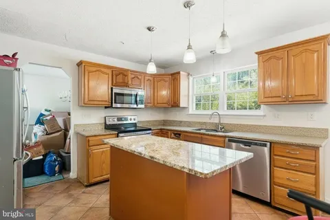 a kitchen with stainless steel appliances granite countertop a sink dishwasher stove and microwave with wooden cabinets