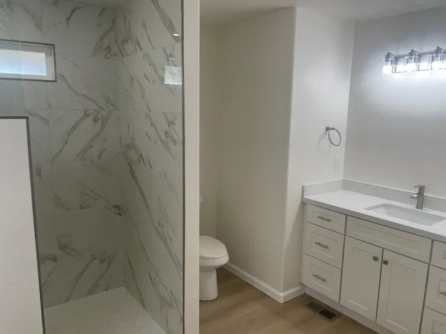 a bathroom with a granite countertop sink toilet and shower