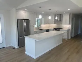 a large kitchen with stainless steel appliances kitchen island granite countertop a refrigerator a stove a sink and a oven with wooden floor