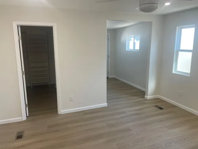 an empty room with wooden floor closet and windows