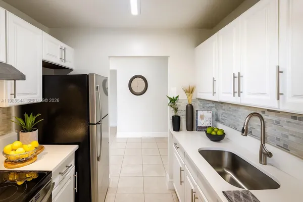 a kitchen with stainless steel appliances a sink a refrigerator a counter space and cabinets