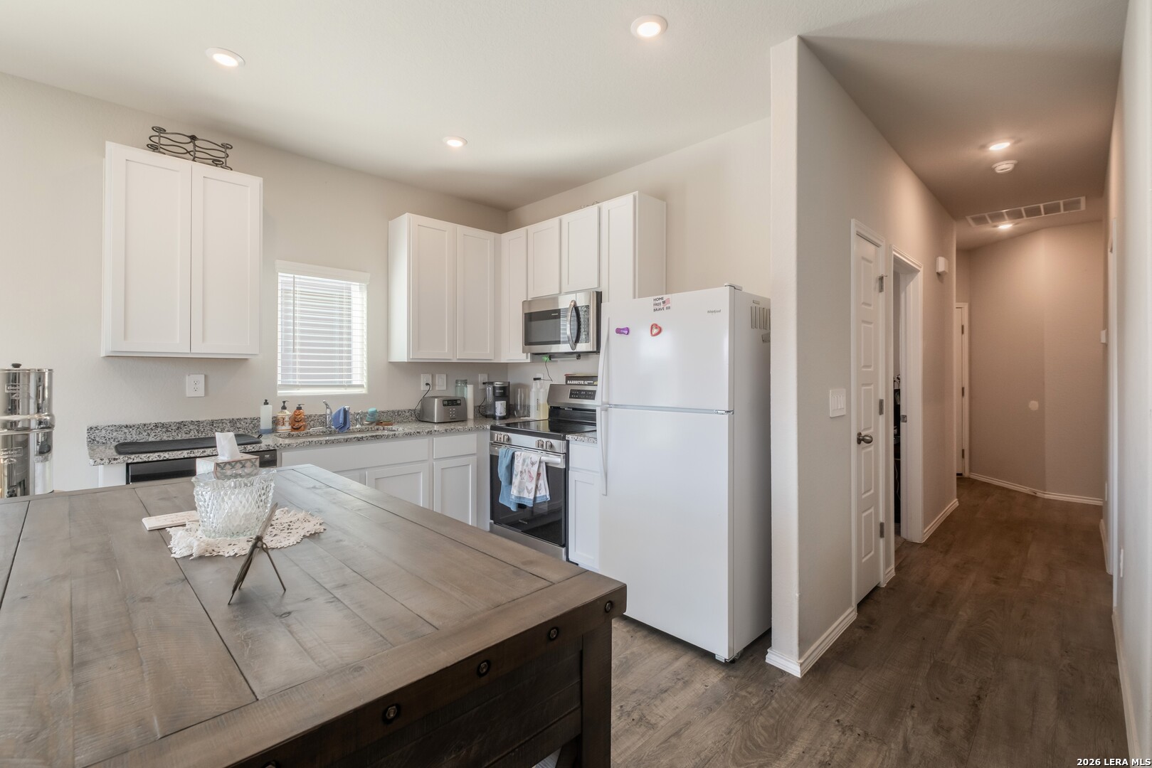 3505 Sky Place Seguin, TX 78155 - Photo 11 of 30 a kitchen with a refrigerator a stove and white cabinets with wooden floor