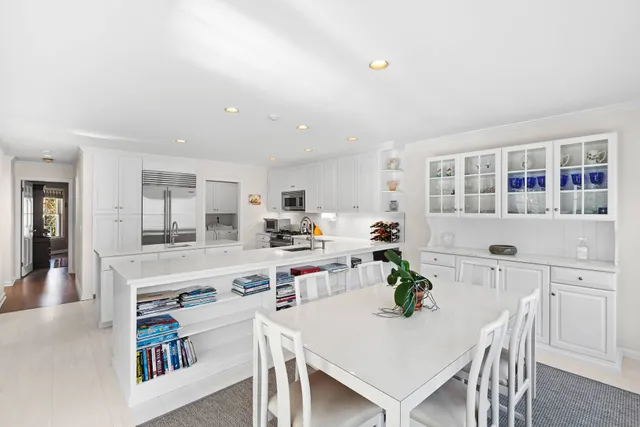a living room with stainless steel appliances furniture a dining table and kitchen view