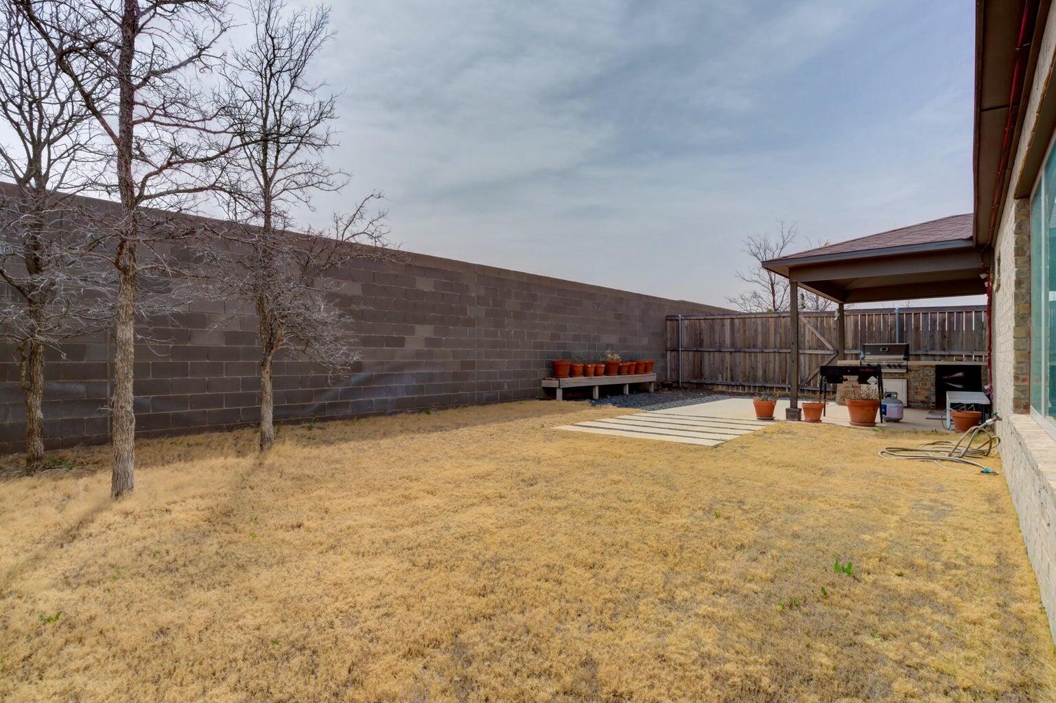 3711 128th Street Lubbock, TX 79423 - Photo 40 of 42 a view of a backyard with table and chairs a barbeque and wooden fence