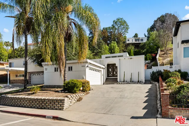 a view of a house with a yard and palm trees