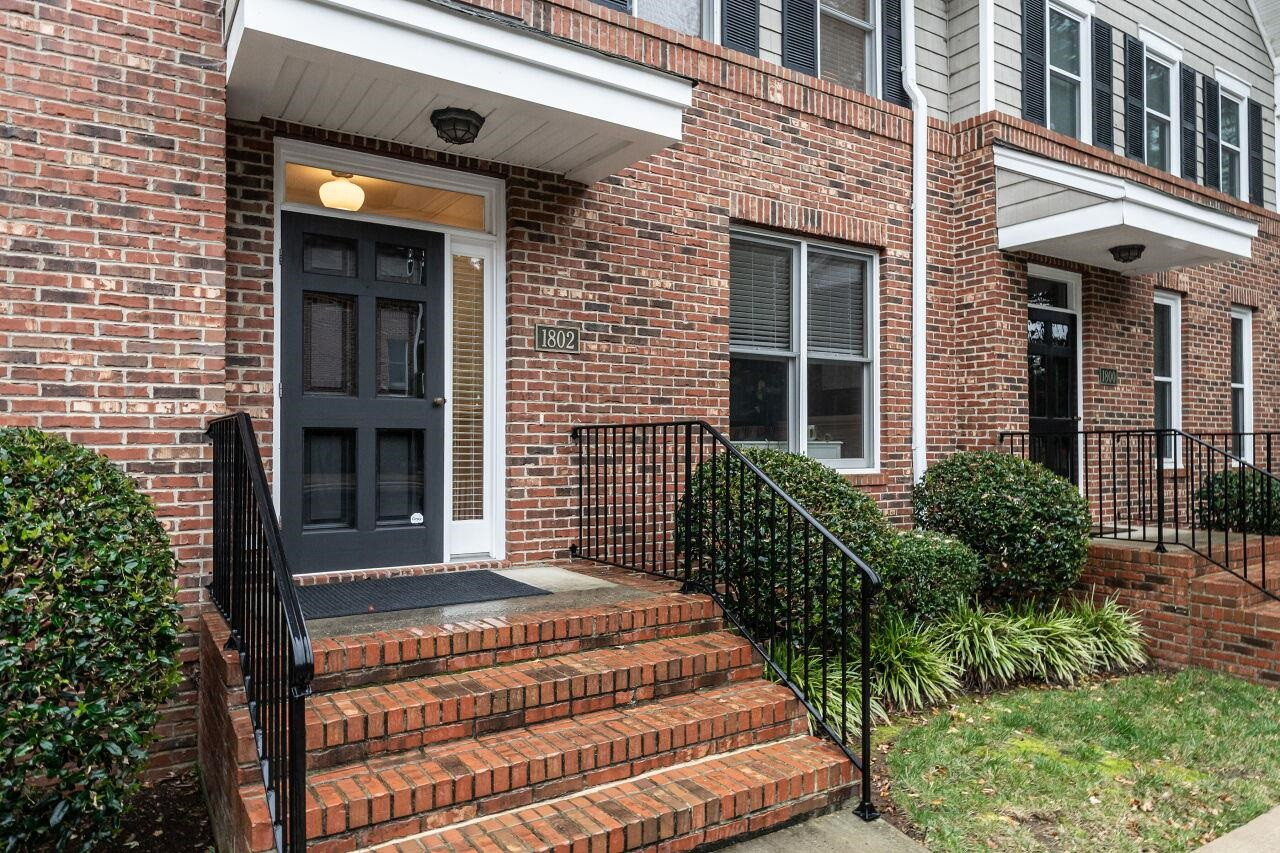 Front porch with wrought iron handrails. Front door with transom, sidelights and storm door. Porch