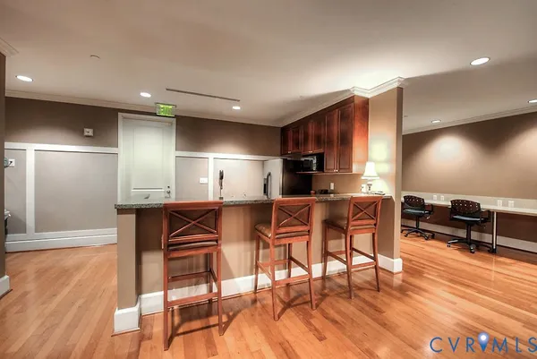 a kitchen with stainless steel appliances kitchen island granite countertop a dining table chairs and a refrigerator a sink with wooden floor