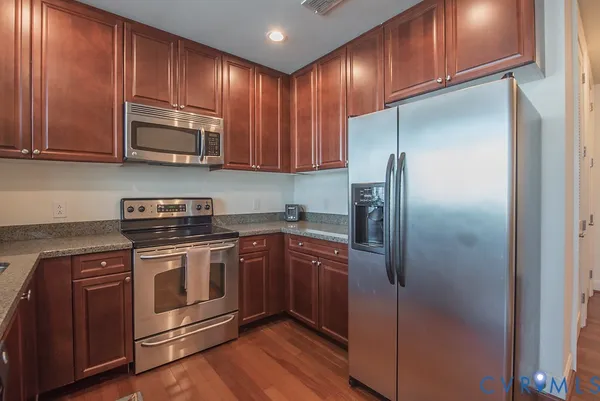 a kitchen with stainless steel appliances granite countertop a refrigerator stove and cabinets