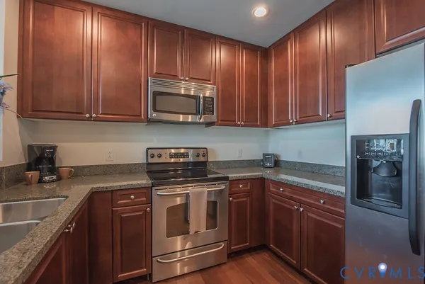 a kitchen with stainless steel appliances granite countertop wooden cabinets a stove top oven a sink and dishwasher