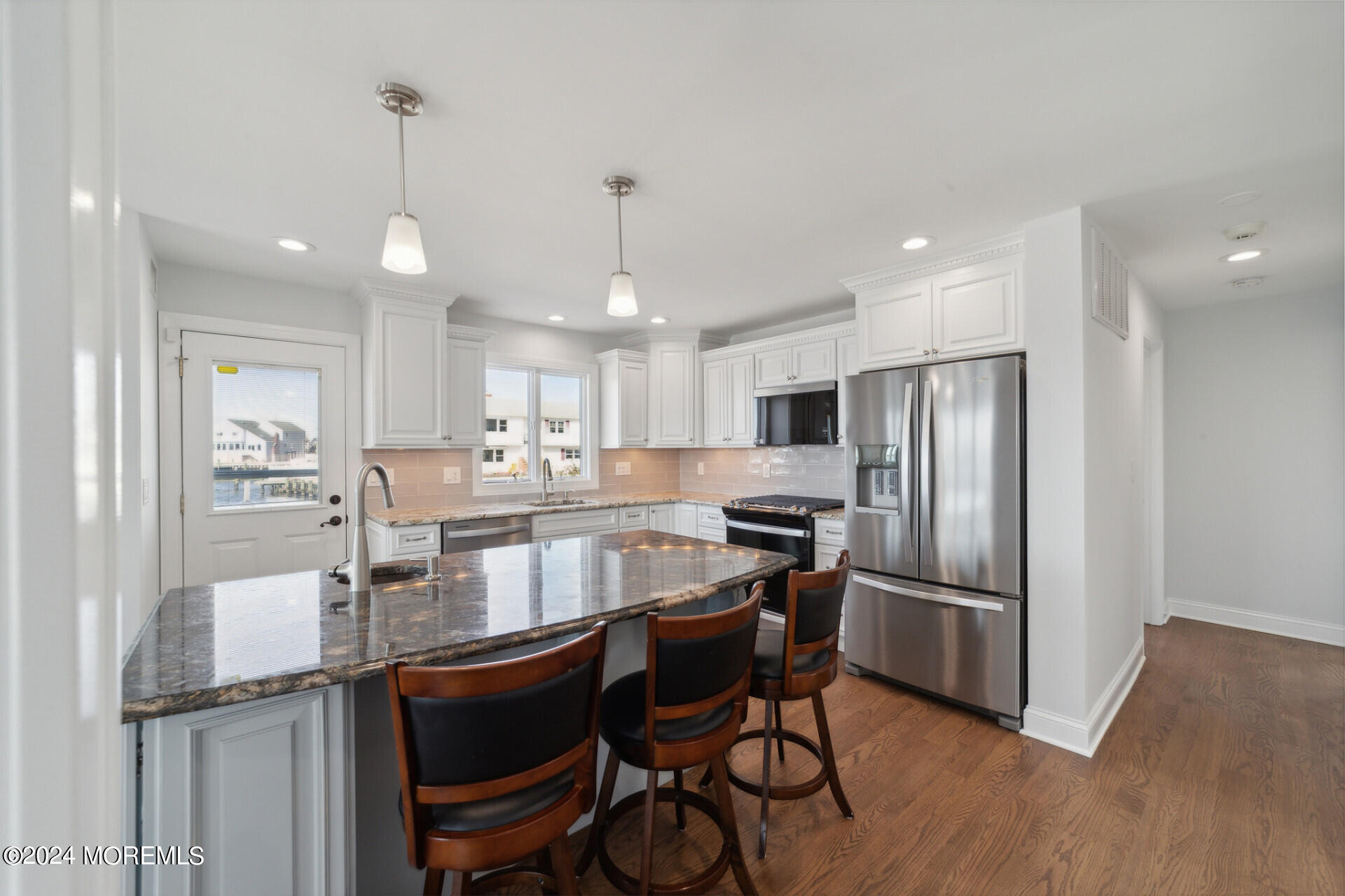 4 Neptune Road Toms River, NJ 08753 - Photo 7 of 24 a kitchen with stainless steel appliances granite countertop a dining table chairs refrigerator and wooden floor