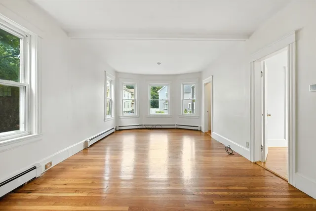 a view of an empty room with wooden floor and windows