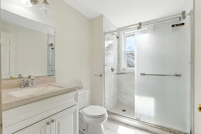 a bathroom with a shower sink vanity mirror and toilet