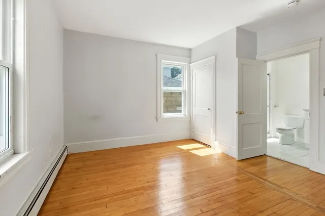 a view of an empty room with window and wooden floor
