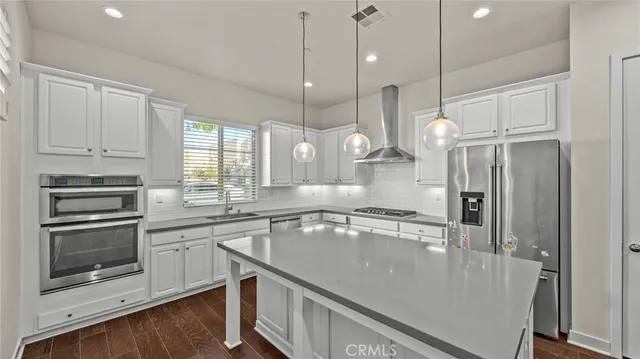 a large kitchen with stainless steel appliances granite countertop a sink a stove and a refrigerator