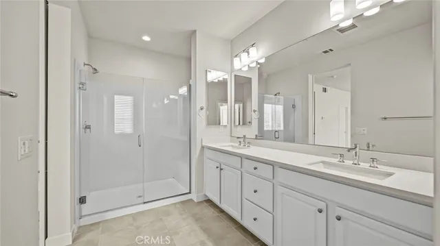 a bathroom with a double vanity sink mirror and shower