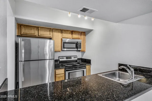 a kitchen with stainless steel appliances granite countertop a refrigerator a stove and a sink