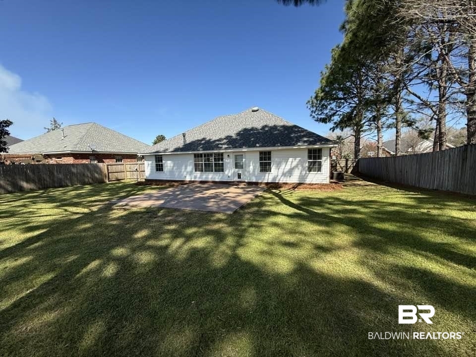 10428 South Side Loop Fairhope, AL 36532 - Photo 4 of 28 Rear view of house featuring a lawn, a patio area, and a fenced backyard
