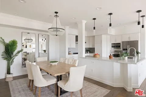 a kitchen with stainless steel appliances kitchen island granite countertop a dining table chairs and white cabinets