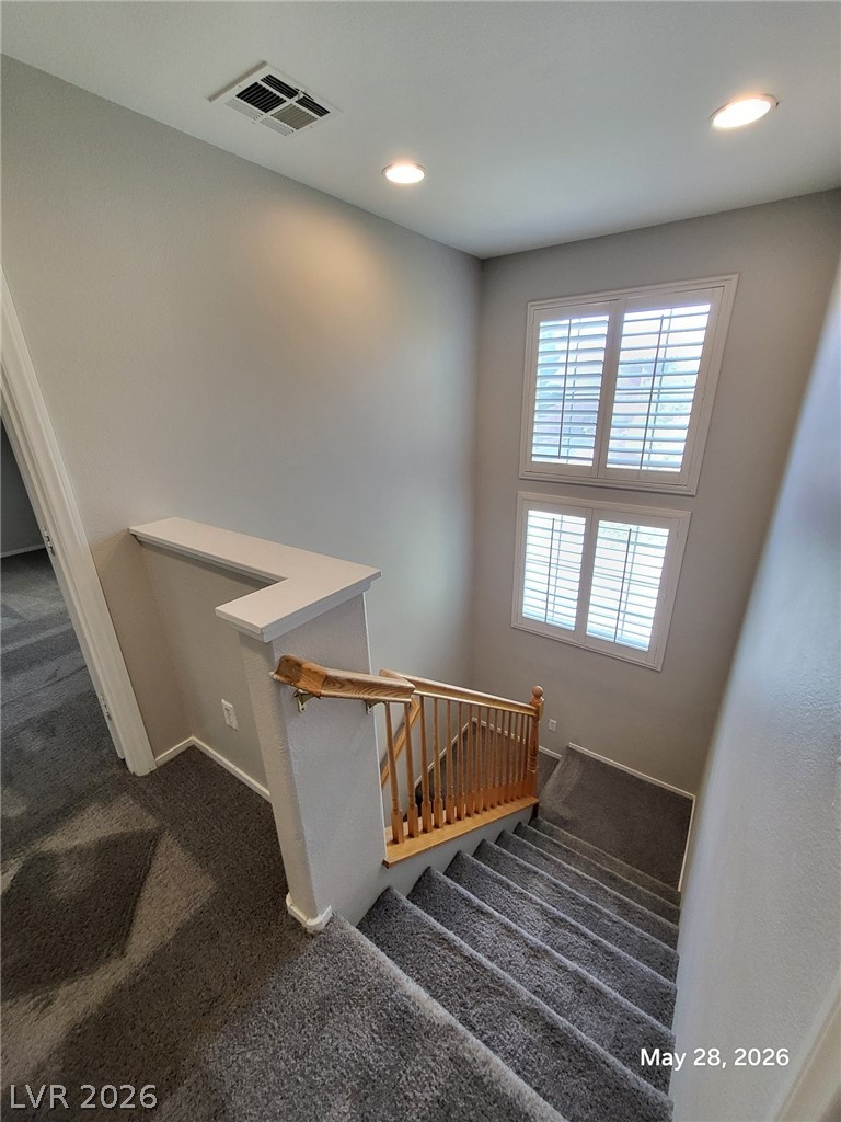 9843 West Overlook Ridge Avenue Las Vegas, NV 89148 - Photo 11 of 19 Two levels of natural light illuminate the stairway, highlighting the cozy carpeted steps and wooden banister.