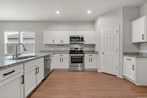 a kitchen with granite countertop white cabinets and stainless steel appliances