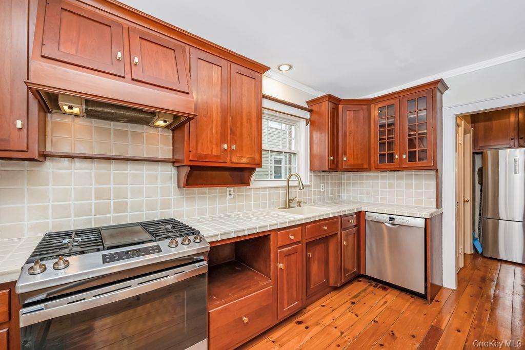 315 Marcellus Road Mineola, NY 11501 - Photo 7 of 18 a kitchen with stainless steel appliances granite countertop a stove a sink dishwasher and cabinets with wooden floor